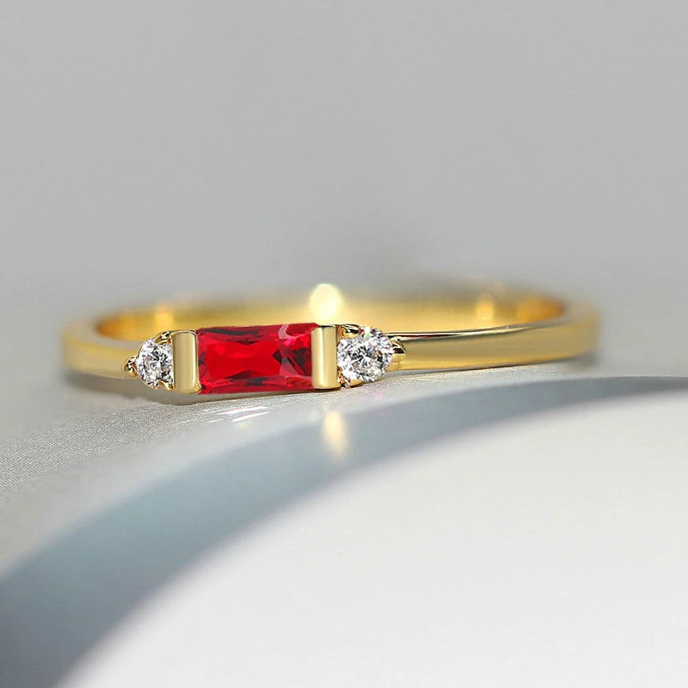 Anillo dorado brillante con piedra central roja