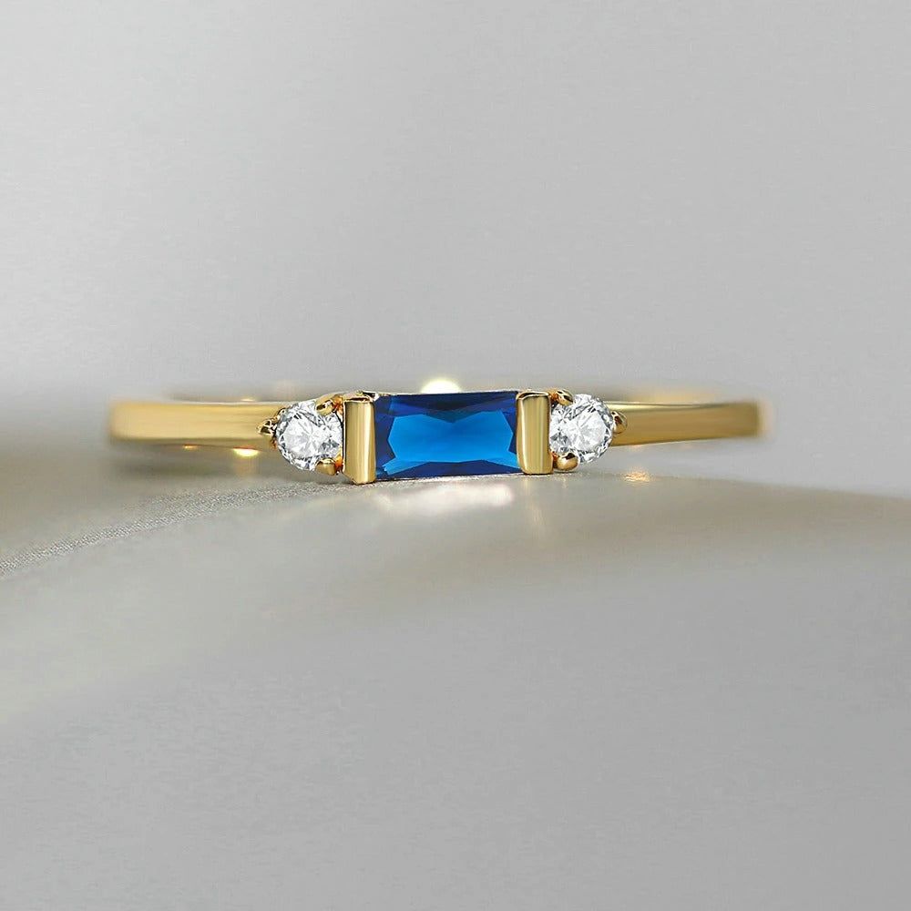 Anillo dorado brillante con piedra central azul